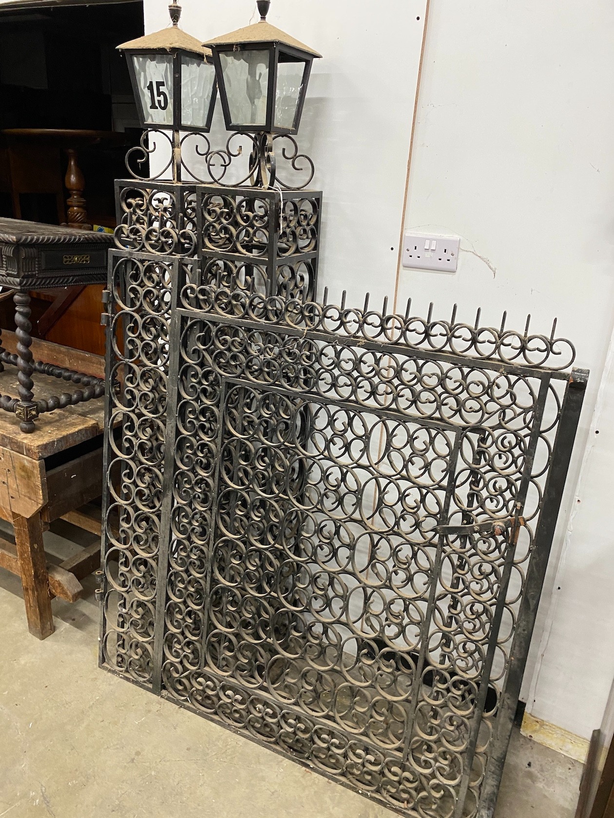 A pair of black painted wrought iron scroll work gates with matching lantern posts, total width 286cm, post height 196cm